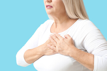 Wall Mural - Mature woman suffering from breast pain on blue background, closeup