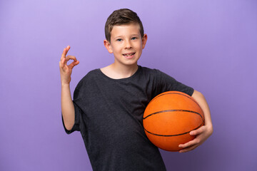 Wall Mural - Little boy playing basketball isolated on purple background showing ok sign with fingers