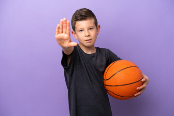 Wall Mural - Little boy playing basketball isolated on purple background making stop gesture