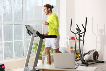 Poster - Sporty young man using laptop for online training in gym