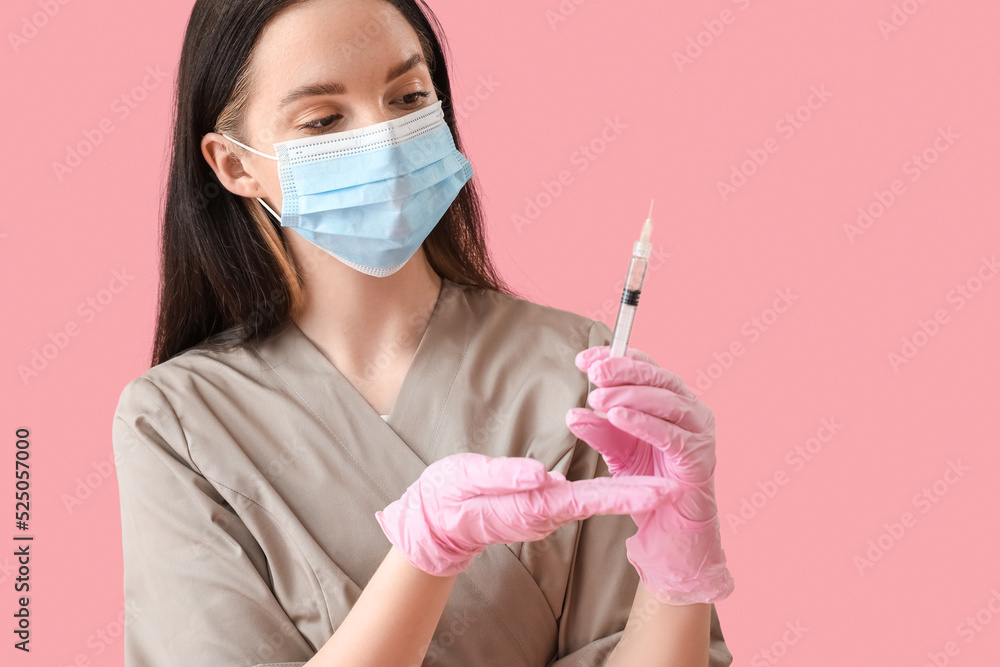 Doctor with syringe on pink background