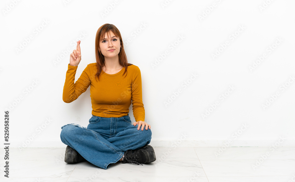 Redhead girl sitting on the floor isolated on white background with ...