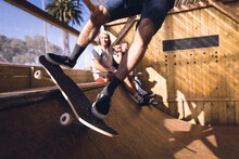 Image Of Low Section Of Caucasian Man Jumping On Skateboard In Skate Park