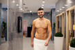 © Dusan Petkovic - A healthy macho man in the spa center. A happy muscular shirtless macho man in a towel walking in the hallway in the spa center and spending the weekend at the resort.