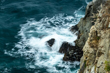 Waves Crash Below A Cliff In Big Sur
