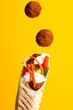 Shawarma with falafel, side view on a yellow background