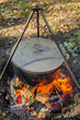 A cauldron covered with a lid in which kulesh is cooked hangs on a tripod over a fire