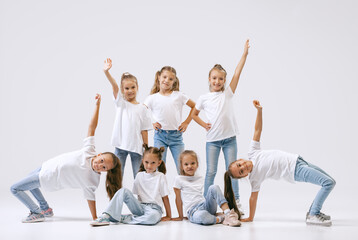 Wall Mural - Active little girls, sportive kids in casual style clothes in motion isolated on white studio background. Concept of music, fashion, art, childhood, hobby