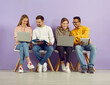 © Studio Romantic - Multiracial students sitting in row on purple background talking and studying with help of gadgets and notebooks. Young people prepare for lecture together using modern gadgets and written notes.