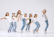 © master1305 - Dance group of happy, active little girls in jeans and t-shirts dancing isolated on white studio background. Concept of music, fashion, art, childhood, hobby