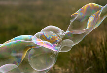 Giant Colourful Soap Bubble Stretching Across A Green Grass Background