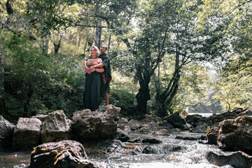 A young couple is kissing on top of a rock barefoot in the river