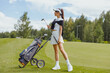 Smiling golfer woman with golf club outdoors on court. Active healthy lifestyle concept