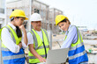 © bigy9950 - Group of contractors, engineers and formats in vests with helmets working with laptop on under-construction site. Home building project. Engineer foreman discusses with coworker at workplace.