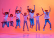 © master1305 - Happy kids, school age girls in white t-shirts and jeans jumping isolated on pink background in yellow neon light.
