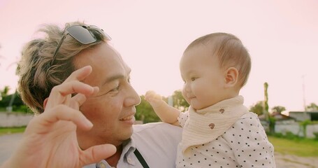 Wall Mural - Portrait Happy family Asian father holding little cute baby child and smiling having fun with sunlight flare sunset sky, beautiful moment emotion love outside nature park summer day, Father's day