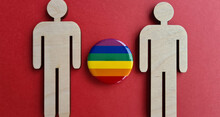 Two Wooden Figurines And LGBT Men On Red Background