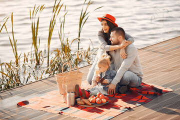 Wall Mural - Family with little daughter sitting near water in a autumn park