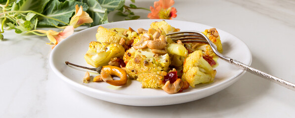 plate with baked cauliflower with cashew nuts on a light table