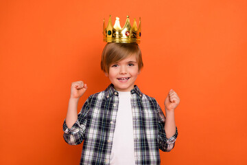 Photo of young excited little boy celebrate luck fists hands prince party isolated over orange color background