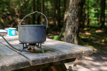 a titanium pot for making food on a gas stove on a camping wooden table in the forest. high quality 