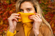 Closeup shot of beautiful blonde natural girl holding turtleneck sweater over her mouth, artistic portrait 