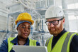 © pressmaster - Two workers of modern factory looking through online information at tablet screen while consulting manual guide in workshop