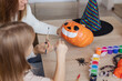 © Julija - mother and little kid daughter making jack-o-lanterns together while preparing for halloween party.