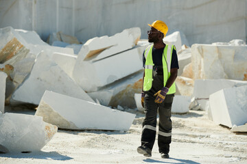 Aufkleber - Front view of young African American male engineer in uniform and safety helmet walking along territory of marble quarry