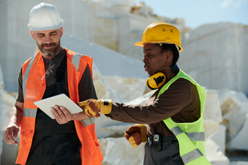 Aufkleber - Young confident female engineer pointing at screen of tablet held by foreman in safety helmet and workwear during work on quarry