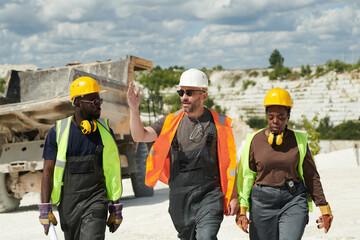 Aufkleber - Confident foreman in workwear explaining something to his African American male and female subordinates on their way to factory