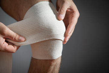 man bandaging an injured knee. first aid and medicine concept