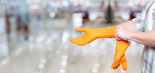 Wall Mural - A cleaning lady puts a rubber glove on her hand .