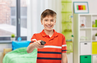 leisure, people and television concept - portrait of happy smiling boy with tv remote control over home room background