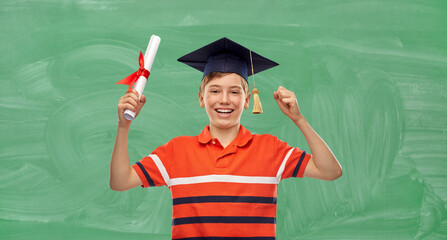 school, education and graduation concept - portrait of happy smiling graduate student boy in bachelor hat or mortarboard with diploma celebrating success over green chalkboard background
