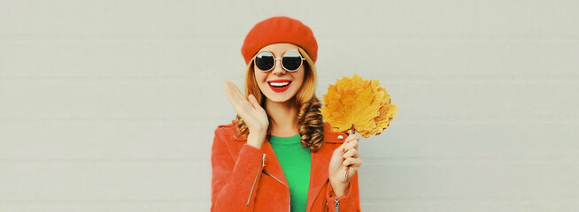autumn portrait of happy smiling young woman with yellow maple leaves wearing red french beret on gr