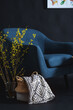 © Syda Productions - interior and home decor concept - close up of blue chair, blanket in wicker basket and branches in vase on floor in dark room