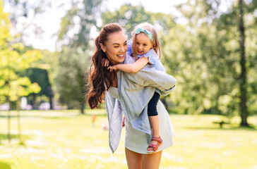 family, motherhood and people concept - happy mother with little daughter having fun at summer park
