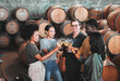 © Kirsten Davis/peopleimages.com - Friends, wine tasting or toasting alcohol with drink glasses in local farm distillery, winery estate or countryside room. Diversity, bonding or happy celebration people together with vineyard barrels