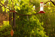 Backyard Hanging Wind Chime and Hummingbird Feeder with Daytime Sunlit Spring Storm Rain Drops