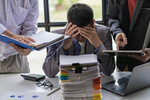 Businessman Stressed With Work With Piles Of Unresolved Documents On Desk In Office