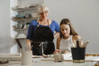 © ninelutsk - Pottery workshop in studio. People working with clay on the table. Adults learning to do ceramic plates. Pottery as hobby and leisure activity