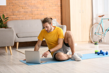 Poster - Sporty young man using laptop for online training at home