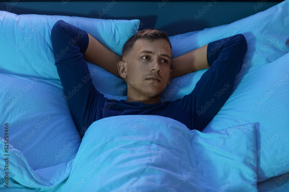 Handsome young man sleeping in bedroom at night