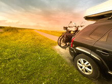 Transport E Bikes By Car.  A Roof Rack Stores Luggage On The Journey.  Sunset. SUV With Gas Tank. 
