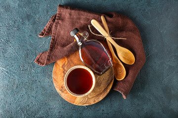 Wall Mural - Composition with bowl and bottle of tasty maple syrup on dark color background