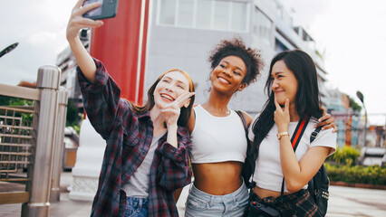 A group of multi-ethnic female friends enjoying the city tour. Young tourists having fun taking pictures together.