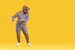Funny eccentric overweight man dancing in strange dinosaur rubber mask isolated on orange background. Fat man in pajamas with leopard print and dinosaur head is having fun near copy space. Web banner.