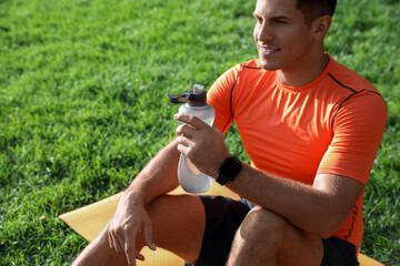 Wall Mural - Man with fitness tracker and bottle of water after training in park