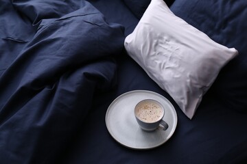 Cup of coffee on bed with stylish silky linens